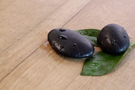 Hot Stones with green leafs on a wooden background