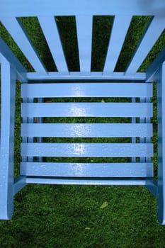 a wooden garden chair with rain drops on the surface