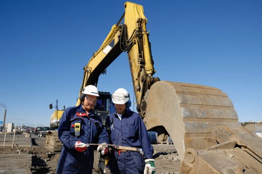 two building workers, engineers with large bulldozer in action