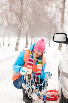 Woman with tire chains car snow breakdown smiling fixing winter