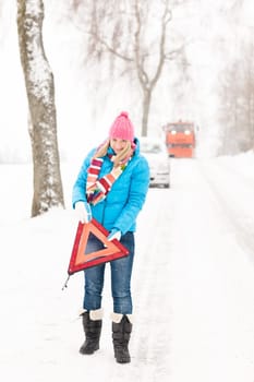 Woman with warning triangle car snow breakdown problem winter traffic