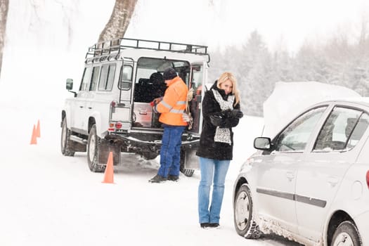 Mechanic helping woman with broken car snow assistance road winter