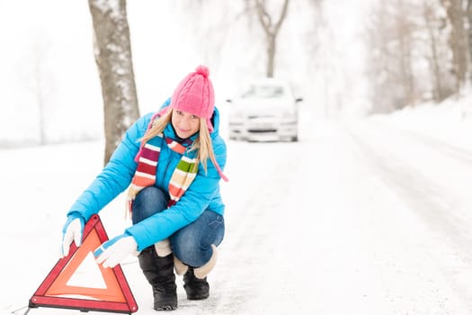 Woman putting reflector triangle car breakdown winter snow sign