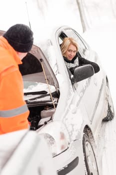 Man repairing woman's car snow assistance winter broken tools mechanic