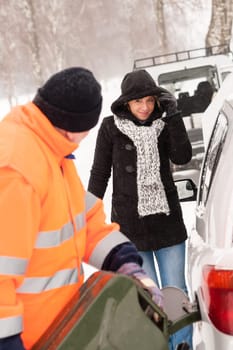 Man filling gas tank car breakdown woman winter snow assistance