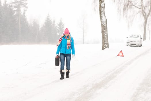 Woman carrying gas can snow car trouble winter breakdown walking