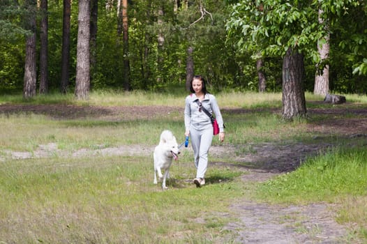 The young woman walks in park with a dog