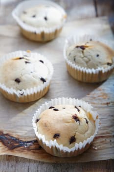 Delicious fresh choc chip cupcakes on a sheet of grungy stained used oven paper