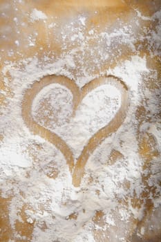 Heart drawn in sprinkled cooking flour symbolic of a love and enjoyment of baking or as a romantic symbol of love for an anniversary or Valentines