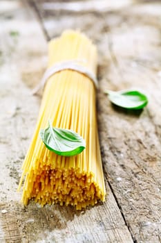 Bundle of uncooked spaghetti with basil for use in the kitchen to prepare fresh Italian pasta dishes