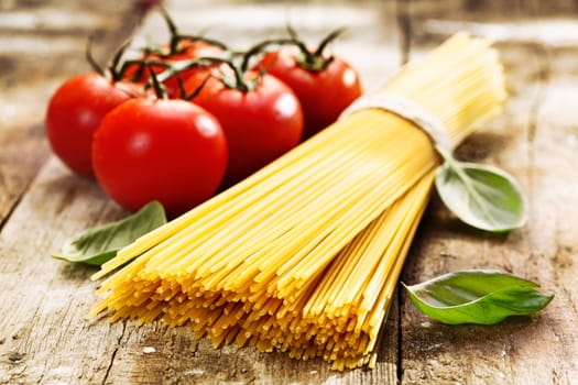 Spaghetti and tomatoes with herbs on an old and vintage wooden table