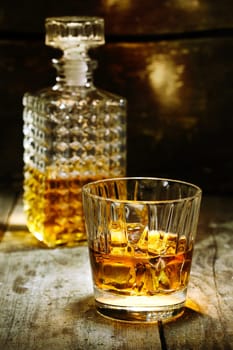 Glass and bottle of hard liquor like scothc, bourbon, whiskey or brandy on wooden background with copyspace