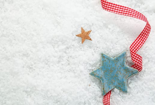 Christmas star background with a decorative red and white checked ribbon on a backdrop of winter snow with copysapce for your seasonal greetings