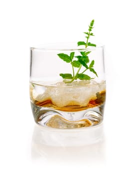 Alcoholic Drink with mint and ice cubes . Hard Liquor in a glass with ice and some herbs isolated on white background