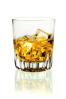 Closeup of a tumbler of glowing golden brandy and ice on a white background with relection