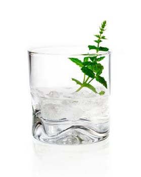 Shot of gin, vermouth or vodka served chilled over ice in a tumbler garnished with fresh herbs on a white background