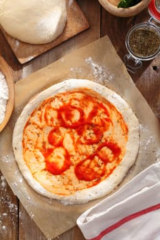 Raw pizza dough on brown wooden table. Preparing pizza for baking