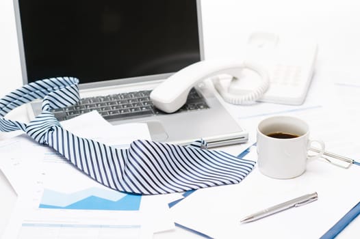 Man's tie laying on business office desk over laptop charts