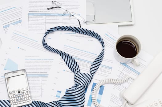 Business tie on busy office desk paper charts, phone coffee
