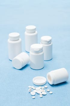 Medicament pills tablets spilled from bottle on medical blue background
