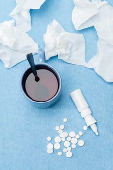 Cold illness medicaments, tea and tissues on blue background