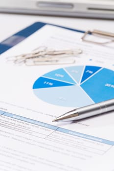 Business silver pen over office paper charts close-up