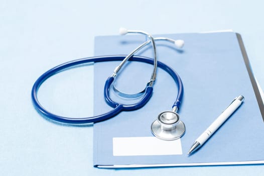 Stethoscope and pen over medical patient chart on blue background