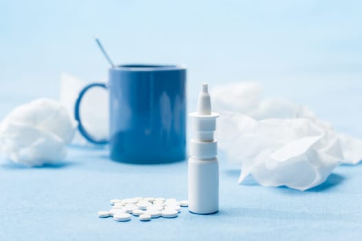 Cold illness medicaments, tea and tissues on blue background
