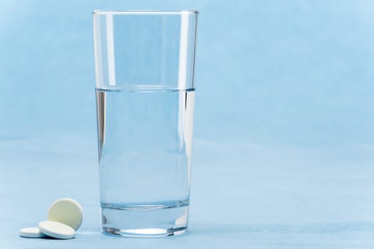 Soluble tablet throw in water glass on blue background