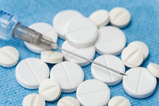 Injection needle with prescription pills blue background