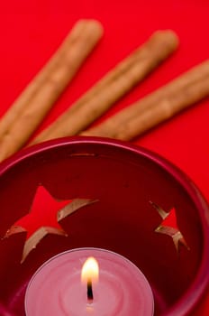 Candle and stars with cinnamon sticks in background