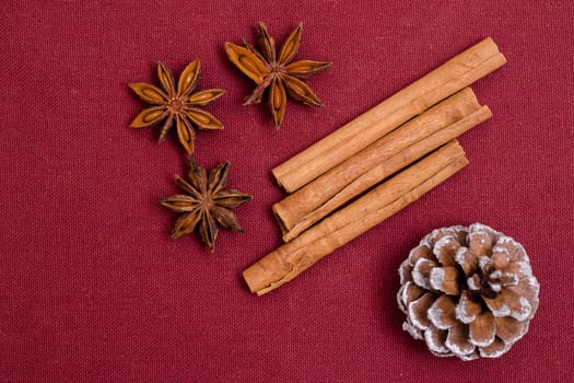 Star anise,cinnamon sticks and pine cones on a red cloth