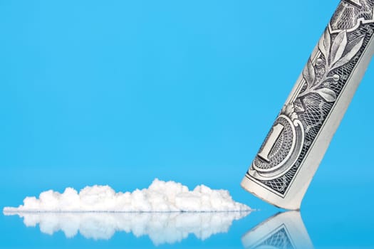Cocaine and dollar with reflection on blue background
