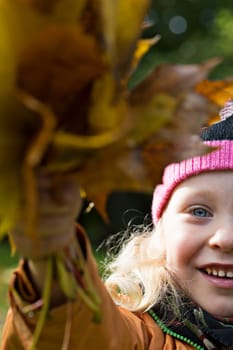 Girl found fallen maple leaves on made bundle