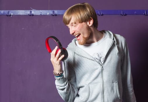 Young man singing to his headphones in cool location