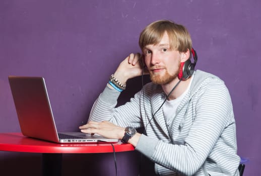Young man sitting working on laptop in cool location location
