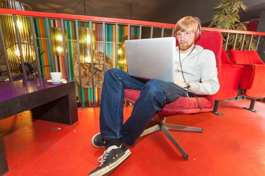 Young man on laptop sitting in lounge
