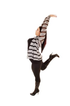 A pretty woman with a full figure standing for white background in tights and black boots, stretching her arms above her heat, showing her figure.