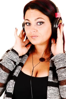 A young pretty woman with headphones, listening to music and looking into  the camera, standing for white background.