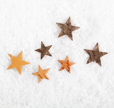 Seasonal or Christmas background of scattered rustic stars on fresh white winter snow with copyspace