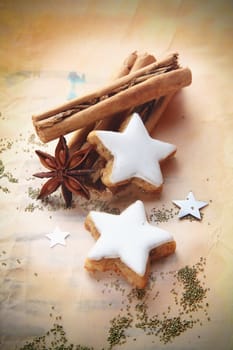 Christmas cinnamon and star anise spice with decorative whited iced star biscuits on vintage paper with vignetting