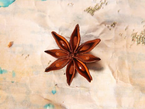 Star anise spice on crumpled aged grungy paper with scattered seeds and copyspace