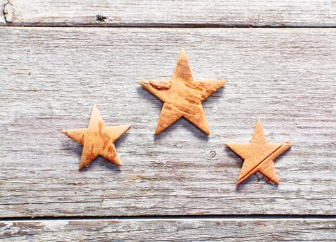 Three decorative Christmas stars on grungy weathered wooden boards with copyspace