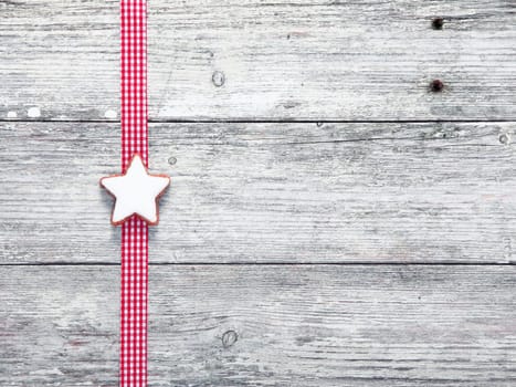 Christmas star biscuit and festive ribbon on grungy white weathered wooden boards with woodgrain texture and copyspace