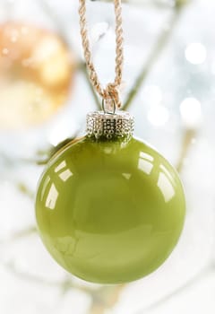 Hanging green Christmas bauble on a golden cord with shallow depth of field and copyspace