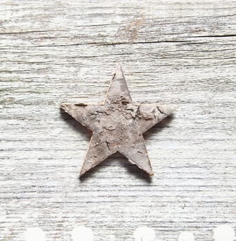 Grungy Christma background with a damaged peeling star centred on old textured cracked and weatherworn wood