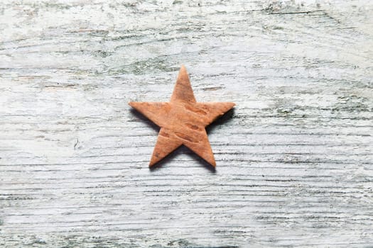 Rustic Christmas star centred on grungy old white weathered wooden boards with grain texture and copyspace