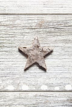Old grungy Christmas star centred vertically on weathered planks with woodgrain and copyspace