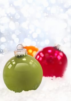Wintery Christmas decorations in a bed of snow with a sparkling bright bokeh of twinkling lights and copyspace