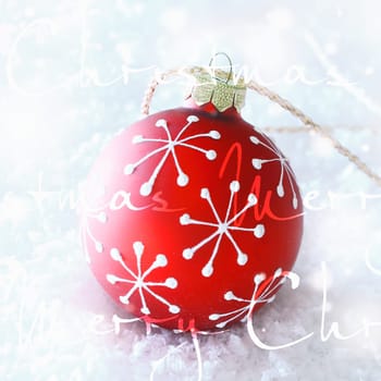 Bright glowing wintery Merry Christmas greeting card with snow and written text superimposed on a decorative red bauble with snowflake decoration